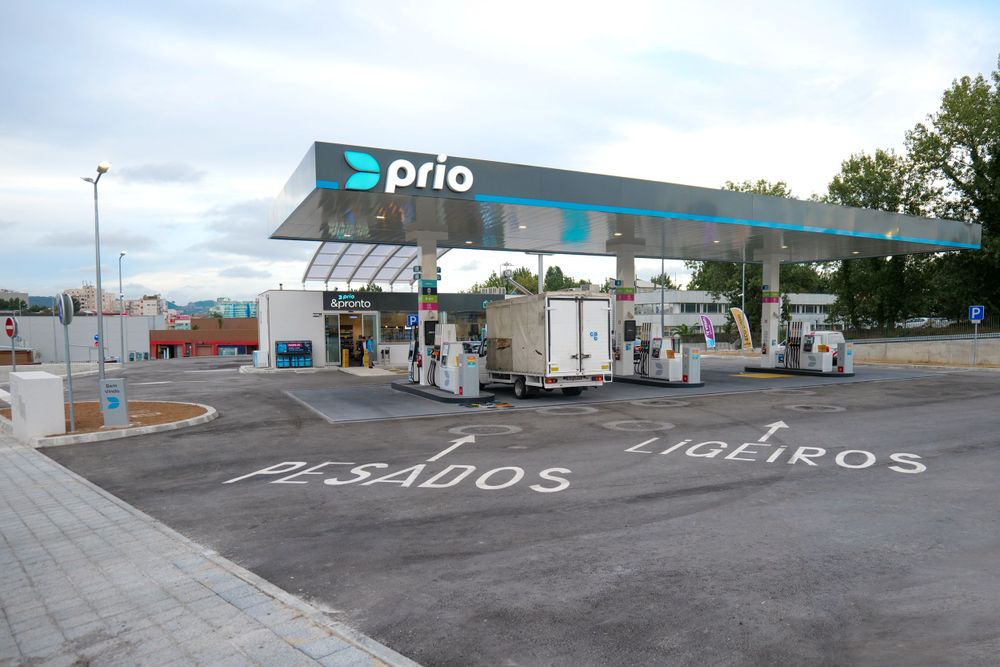 Prio branded fuel station forecourt with canopy showing pesados and ligeiros lanes marked on asphalt.