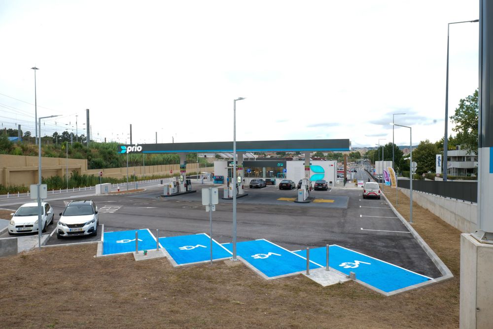 Wide view of Prio gas station with blue disabled parking bays in foreground and fuel pumps under canopy.
