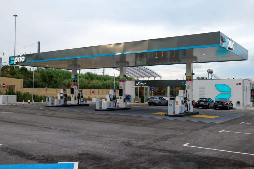 Modern Prio fuel station with large canopy covering multiple fuel dispensers and a tanker truck nearby.