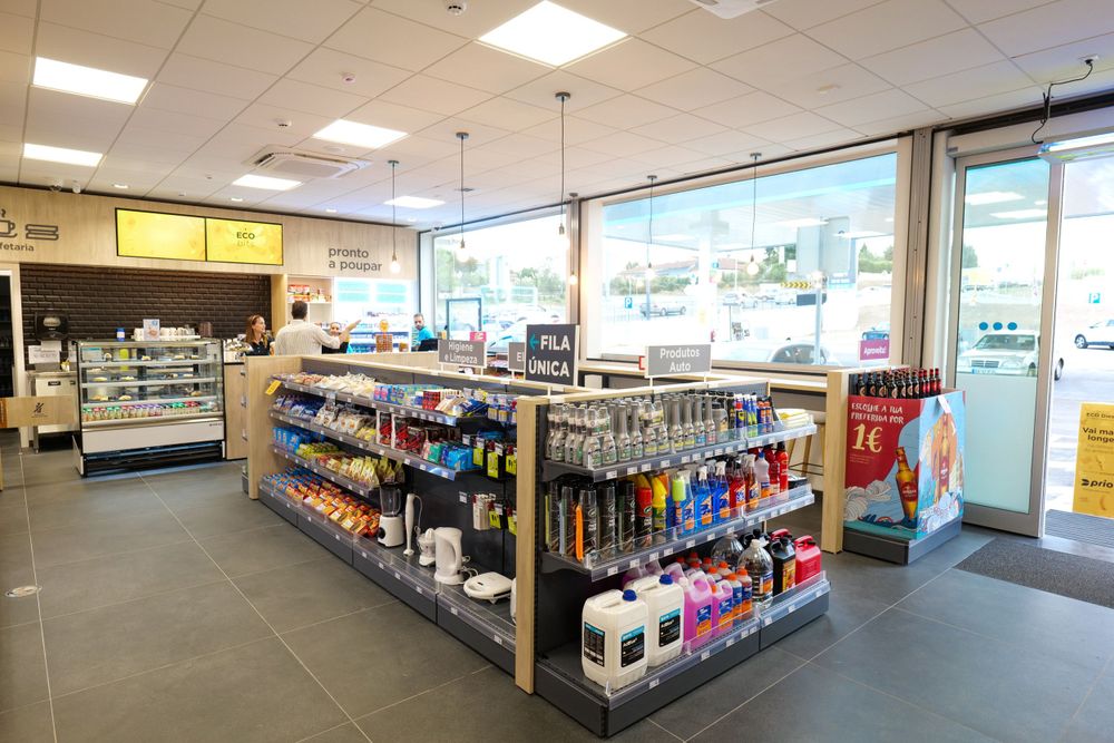 Inside view of Prio fuel station shop with product shelves drinks and a service counter in background.