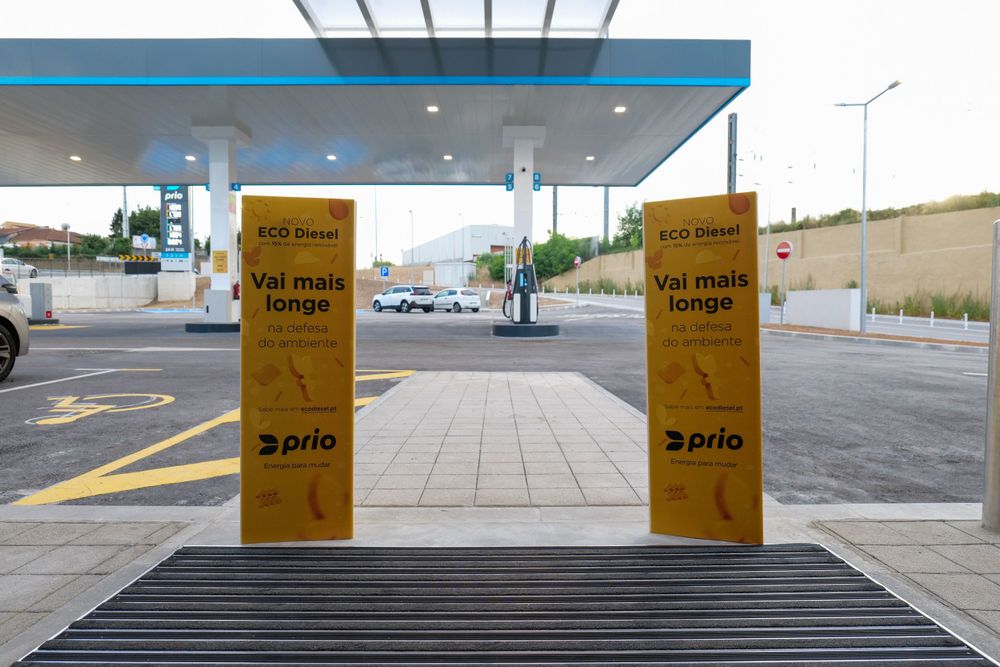 Two yellow Prio promotional banners reading Val mais longe flanking a fuel station entrance walkway.