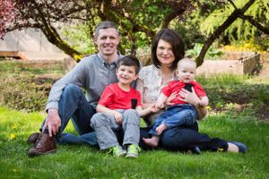 Family of four sitting together on grass during springtime photo session.