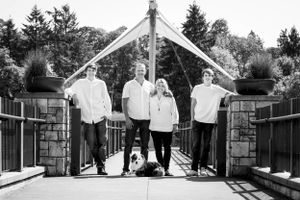 Black and white photo of a group standing on a wooden bridge under an archway.