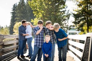 Group of people sharing laughs together on wooden dock during sunny day.