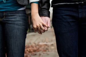 Close-up of two people holding hands while wearing blue jeans.
