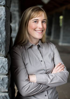 A professional portrait against a stone wall showing confidence and warmth.