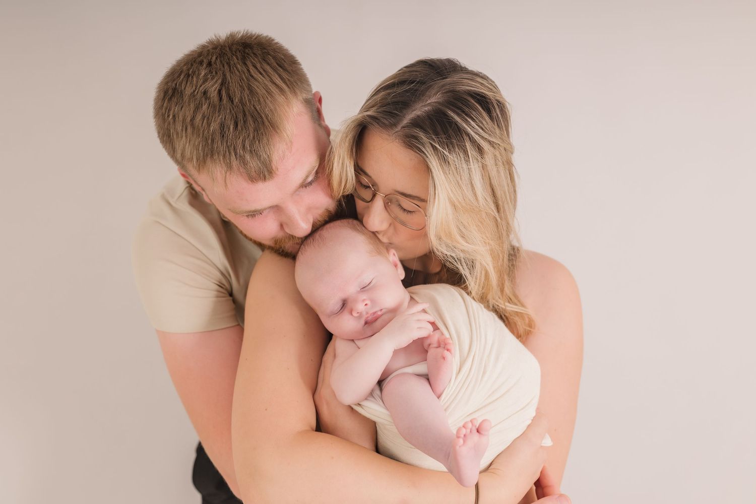 Warm studio portrait of parents embracing their sleeping newborn baby.  Photographer. Hull. East Yorkshire. Photography