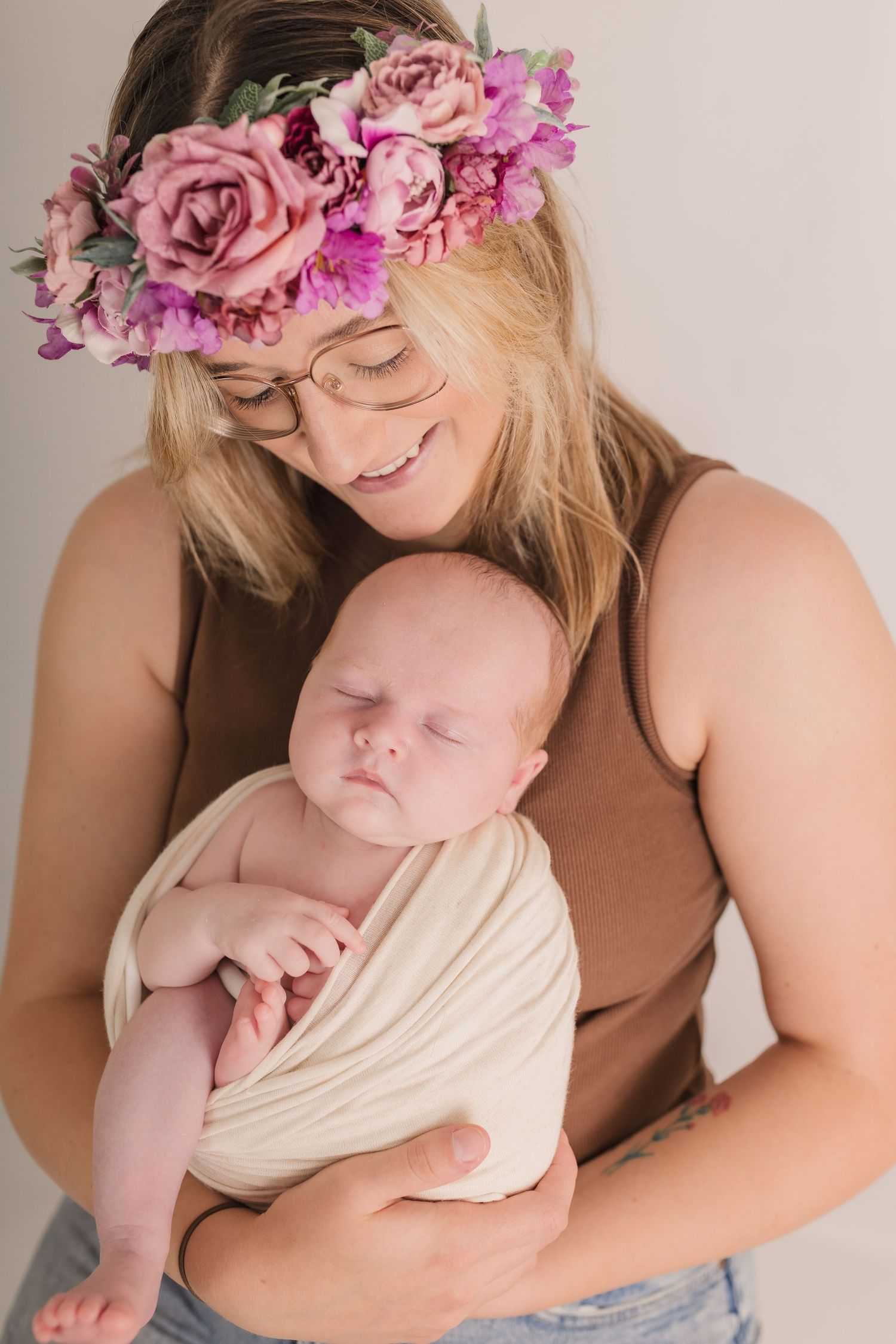 Mother wearing pink floral crown holds sleeping newborn wrapped in cream fabric.  Photographer. Hull. East Yorkshire. Photography