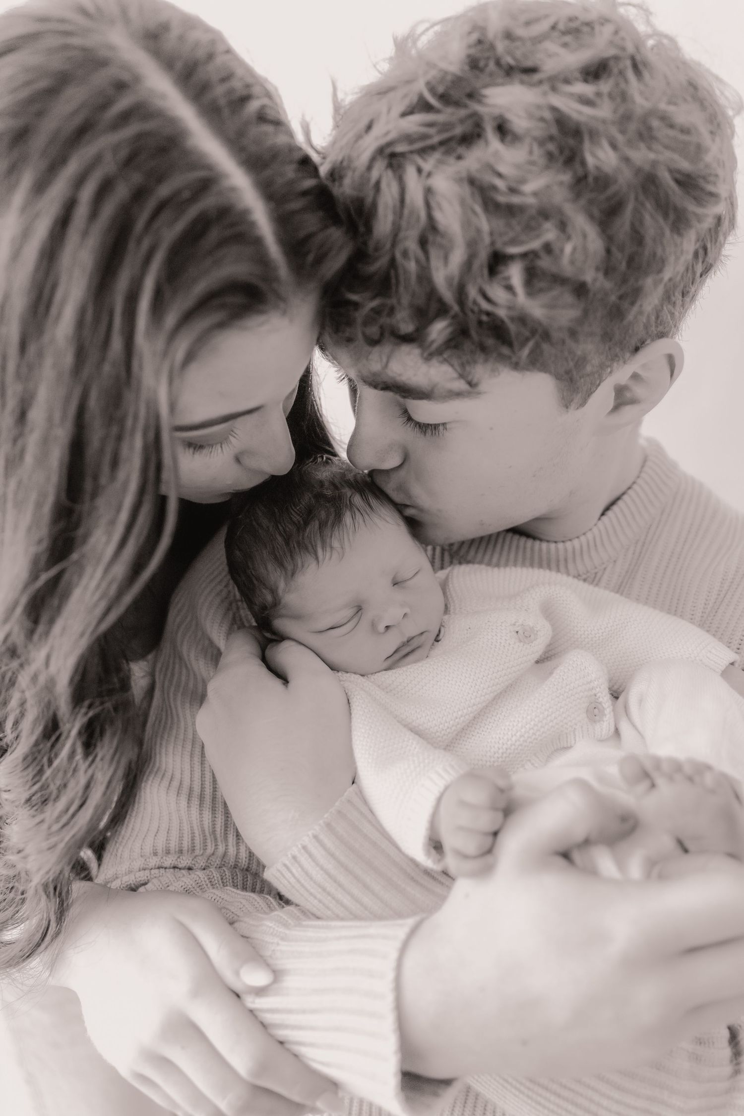 A series of intimate black and white photos showing tender moments between a couple in soft lighting.