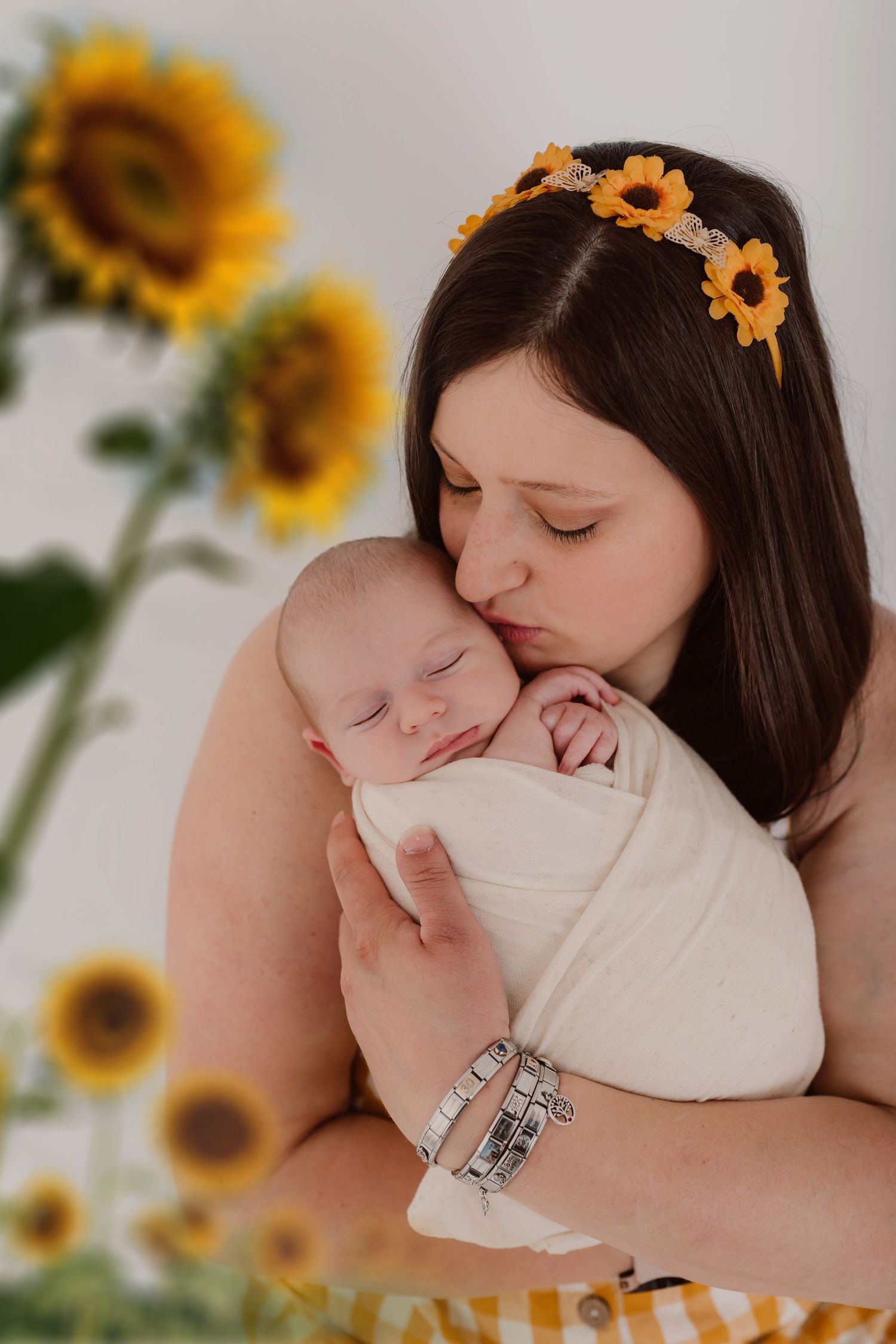 A tender moment between parent and baby with bright sunflowers decorating the background.