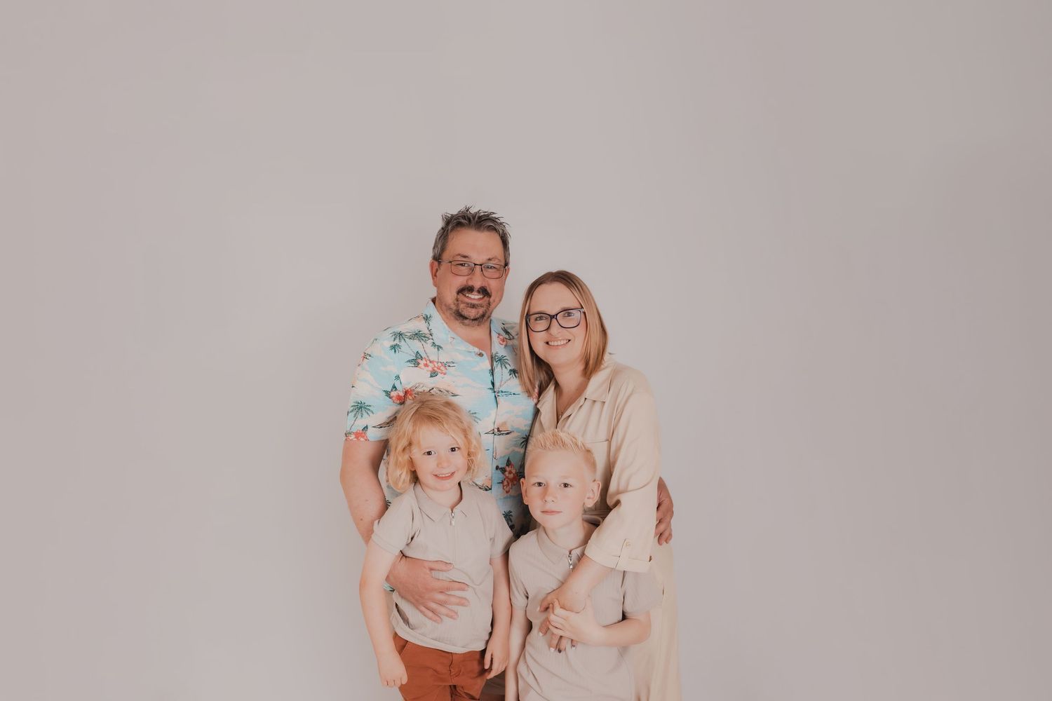 Family portrait session featuring coordinated neutral-toned outfits against a plain backdrop. Photographer. Hull. East Yorkshire. Photograph