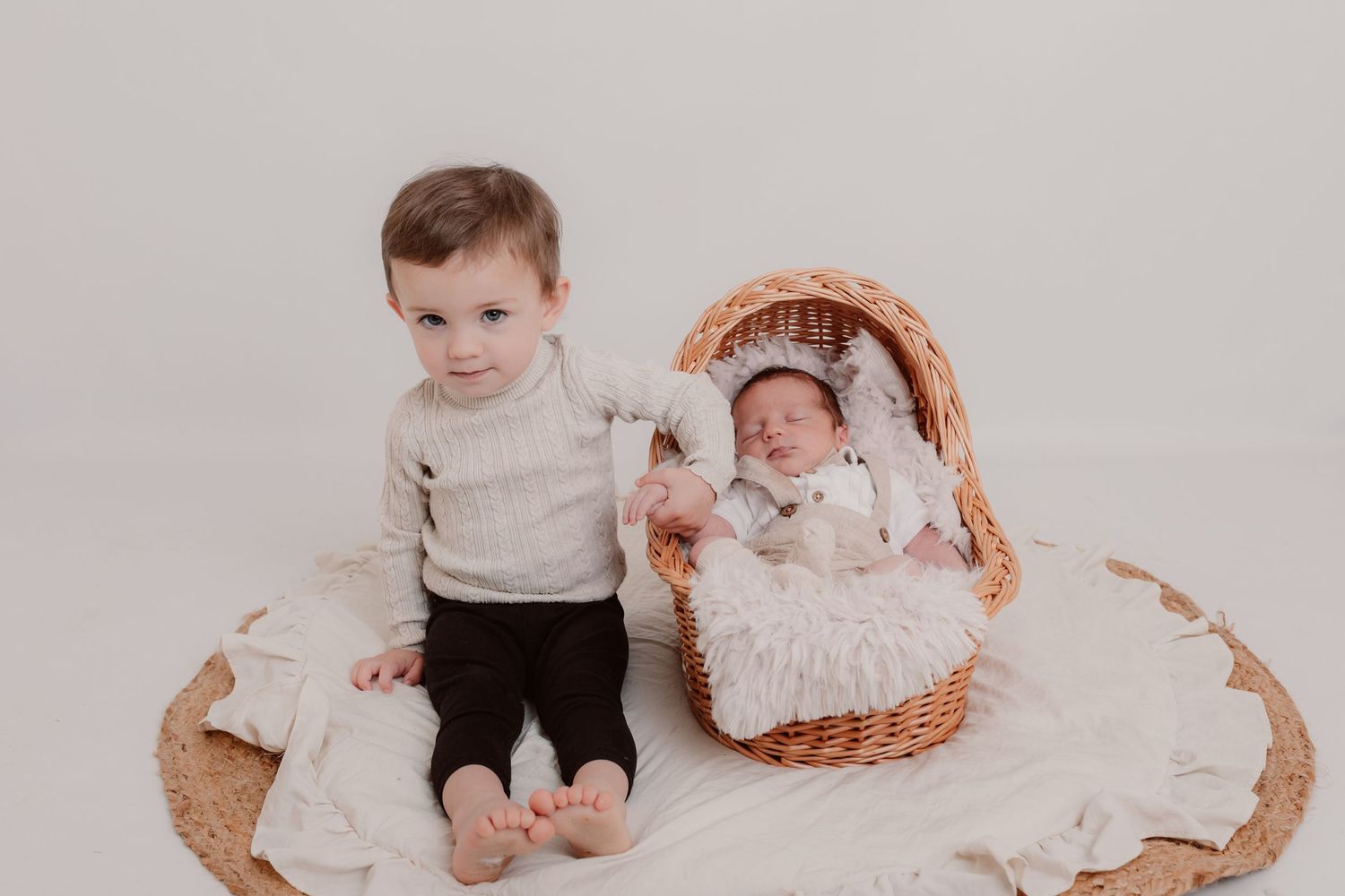 Sweet newborn and toddler siblings bonding together on white textured blankets in a studio setting. Photographer. Hull. East Yorkshire.