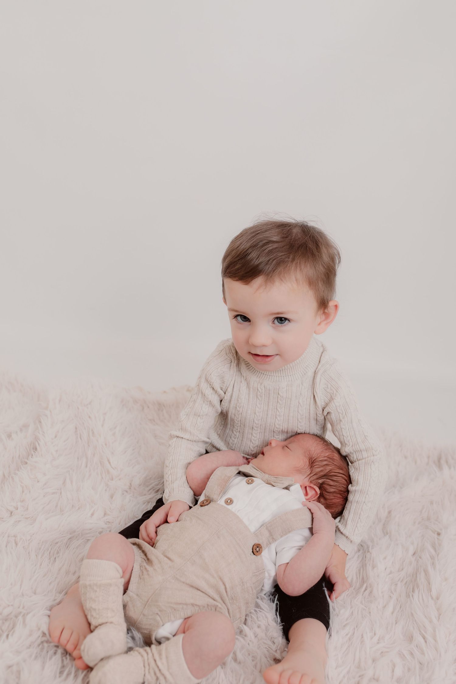 Siblings sharing a tender moment on white bedding during newborn photo session. Photographer. Hull. East Yorkshire. Photography