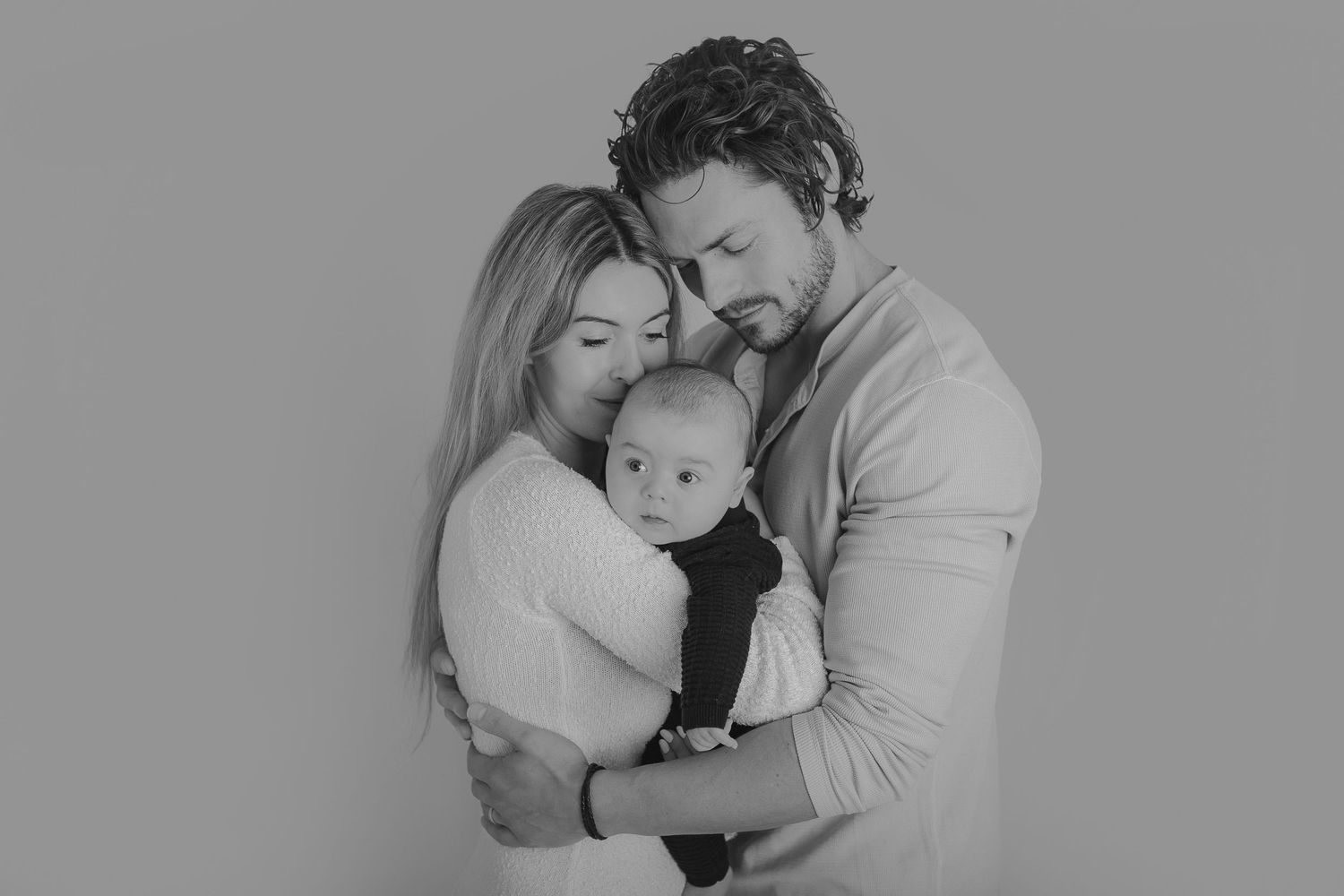 Intimate black and white portrait of parents embracing their newborn baby in a tender moment.  Photographer. Hull. East Yorkshire. Photo
