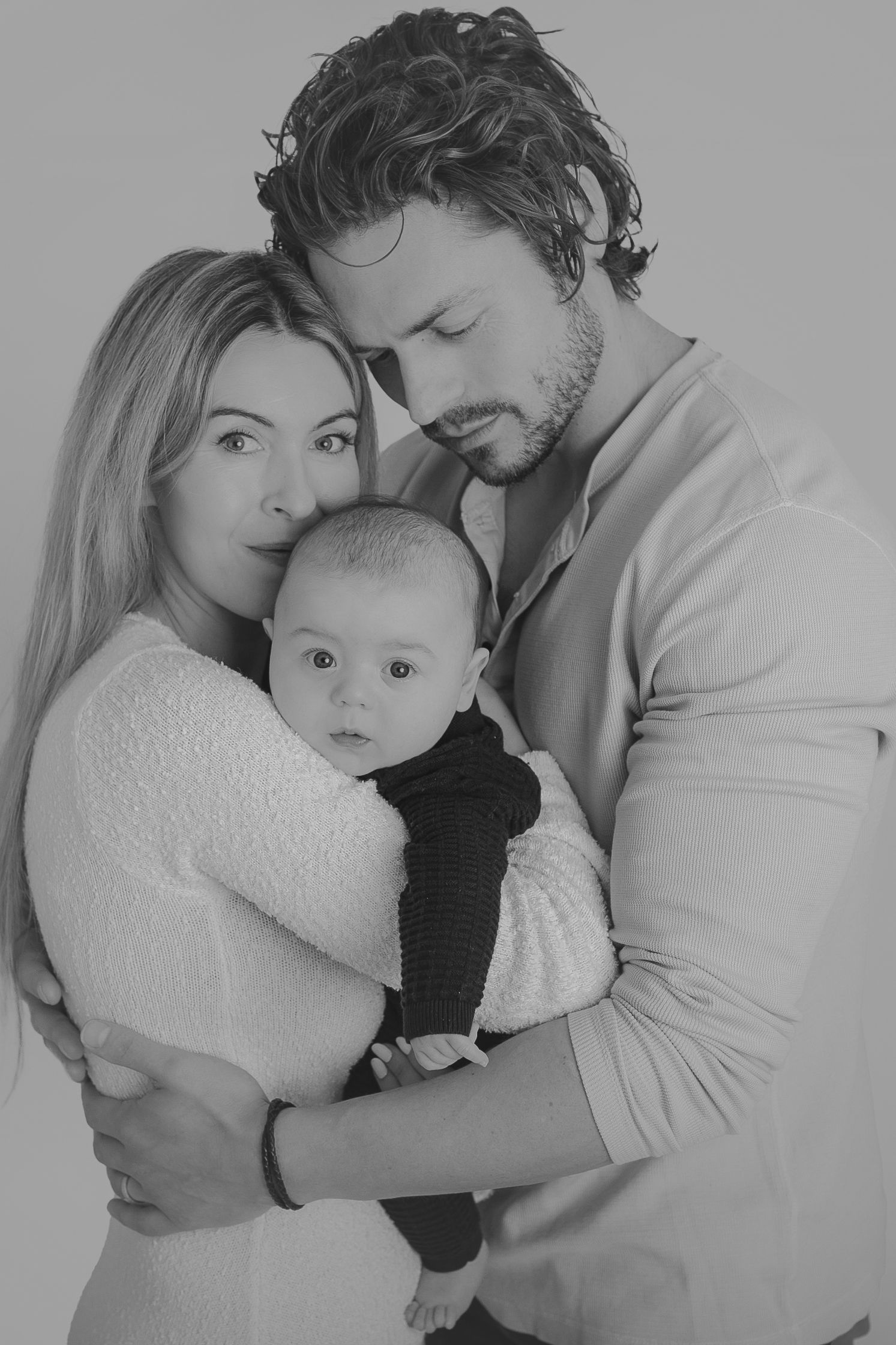 Black and white studio portrait of parents holding their infant child in a loving embrace.  Photographer. Hull. East Yorkshire. Photography