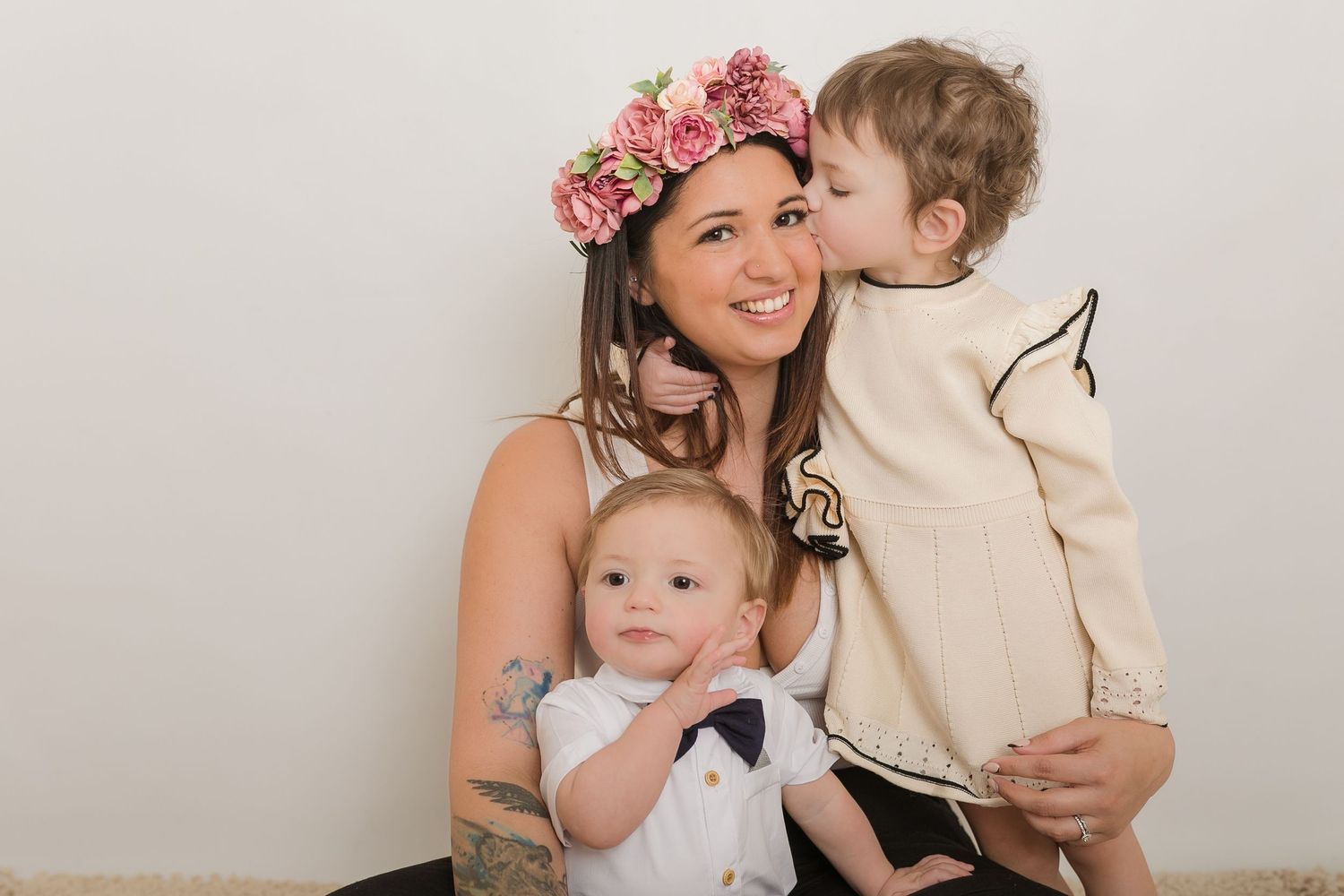 A floral crown adorns a tender family moment against a light gray backdrop. Photographer. Hull. East Yorkshire. Photography