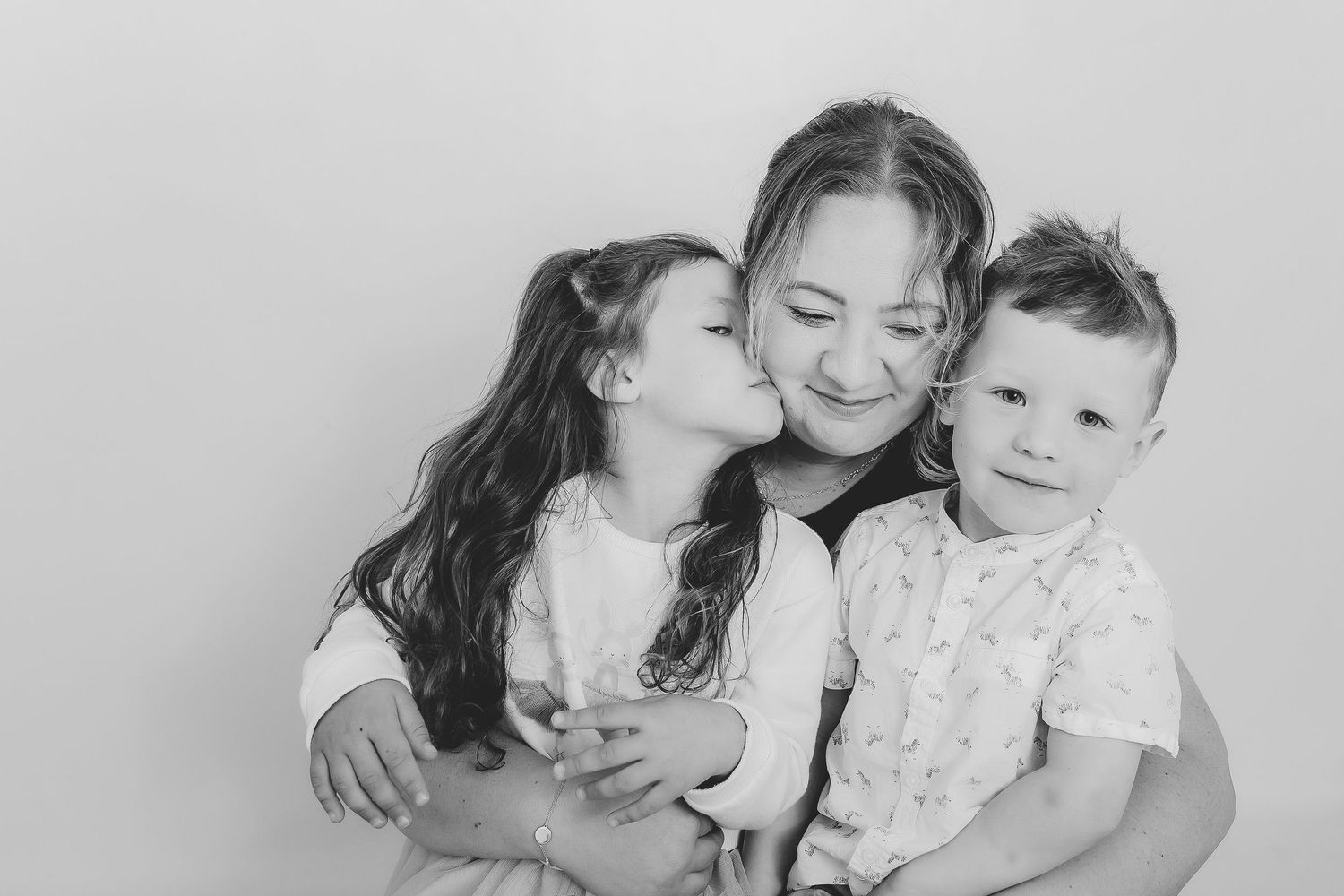 Two siblings sharing a sweet embrace while wearing white outfits against a light background. Photographer. Hull. East Yorkshire. Photography