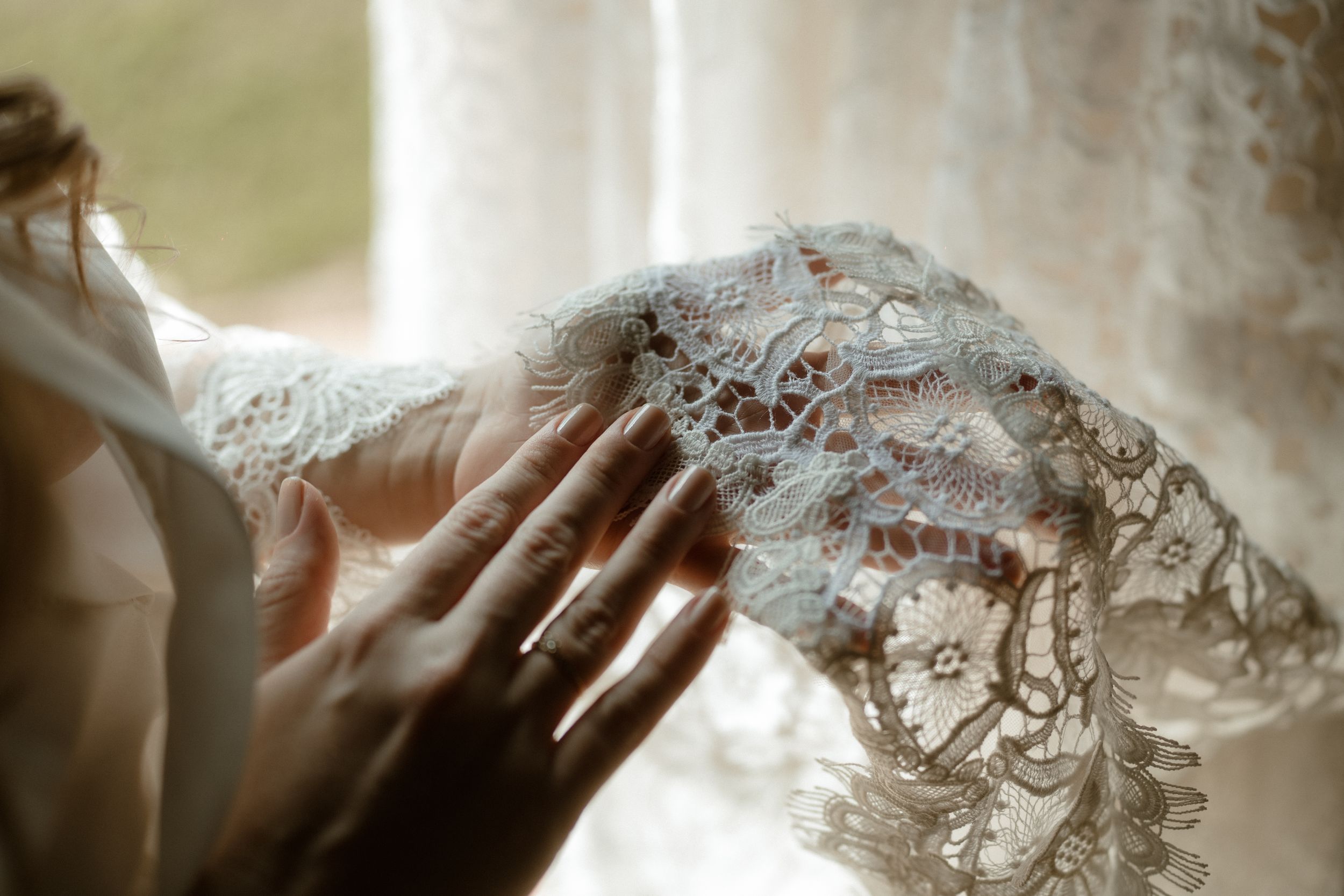 Elegant lace wedding dress details shown in soft natural light.