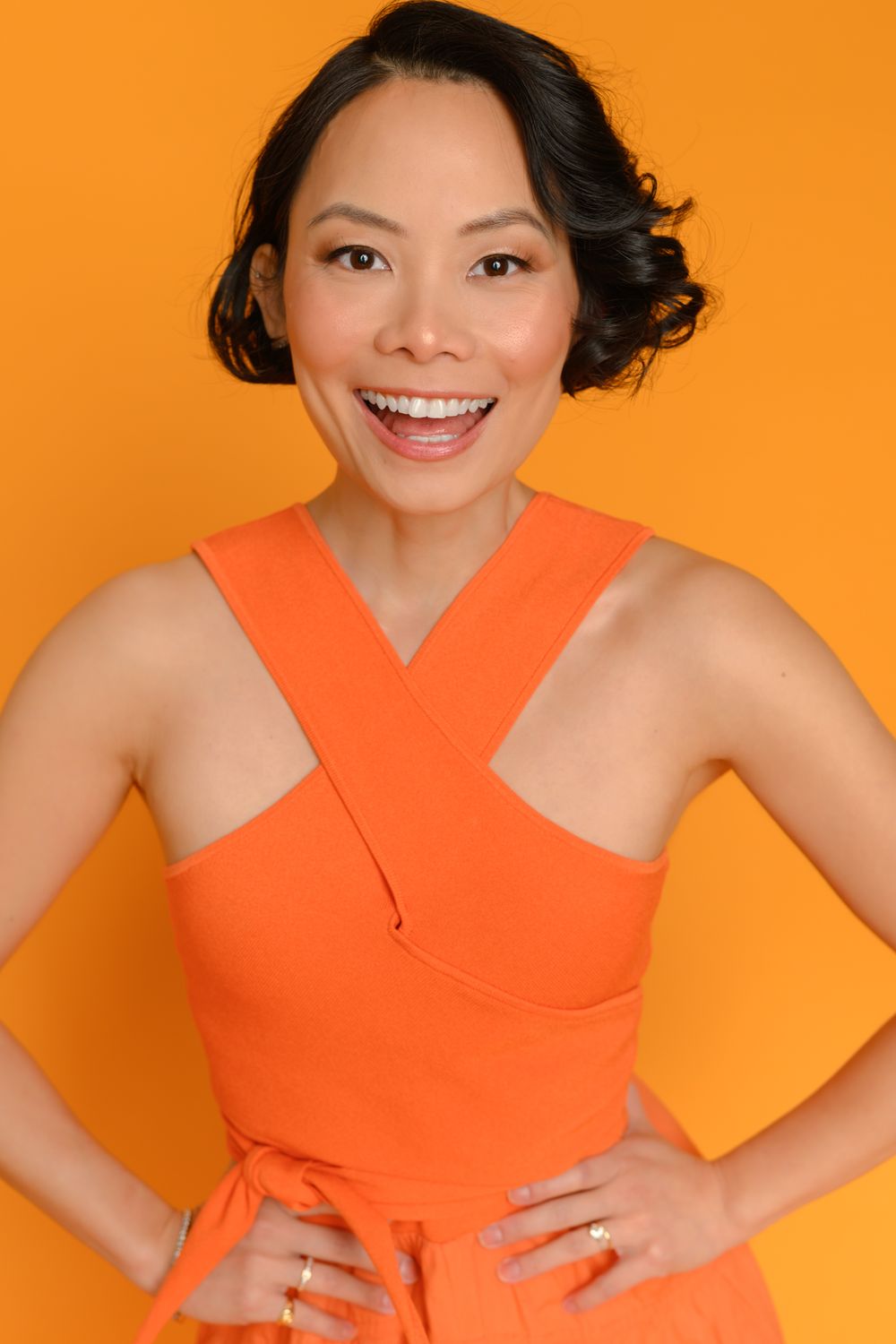 Dynamic portrait series in orange dress against vibrant orange backdrop.
