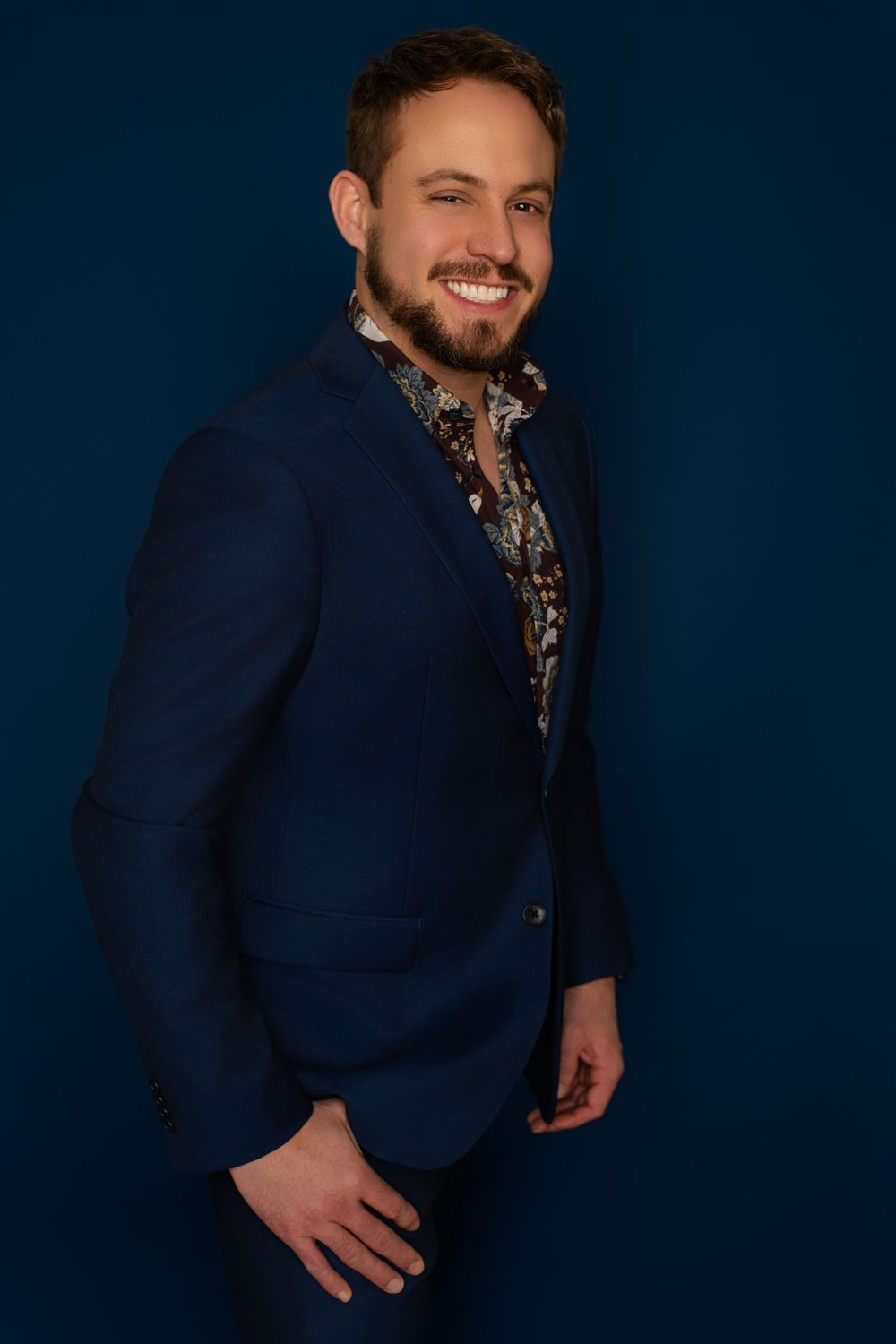 Professional portrait series of someone in a navy suit against a dark background.