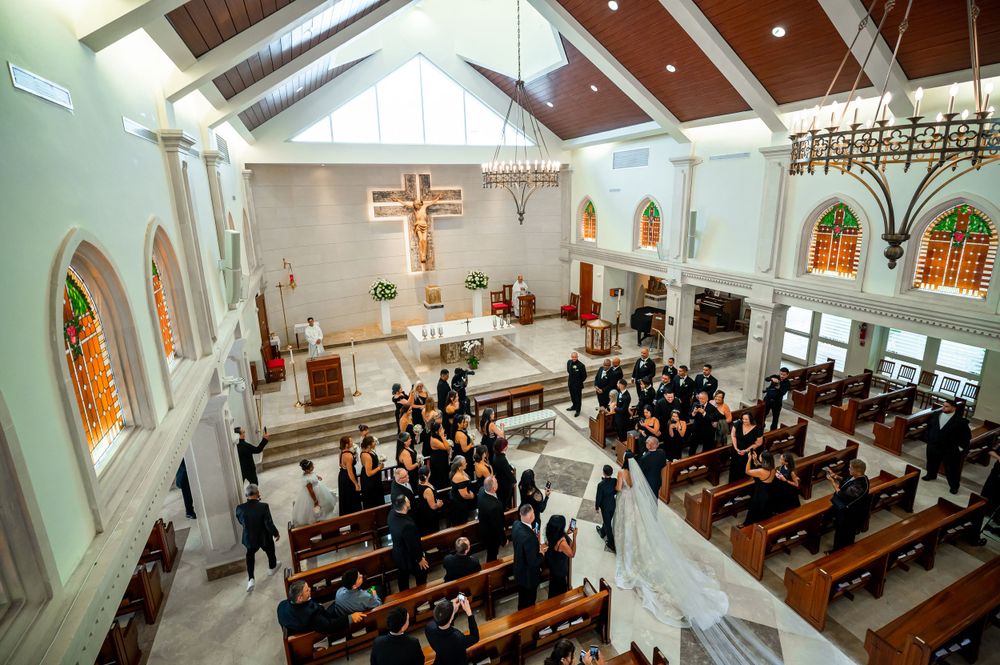 Aerial view of Catholic church wedding ceremony with guests seated in wooden pews.