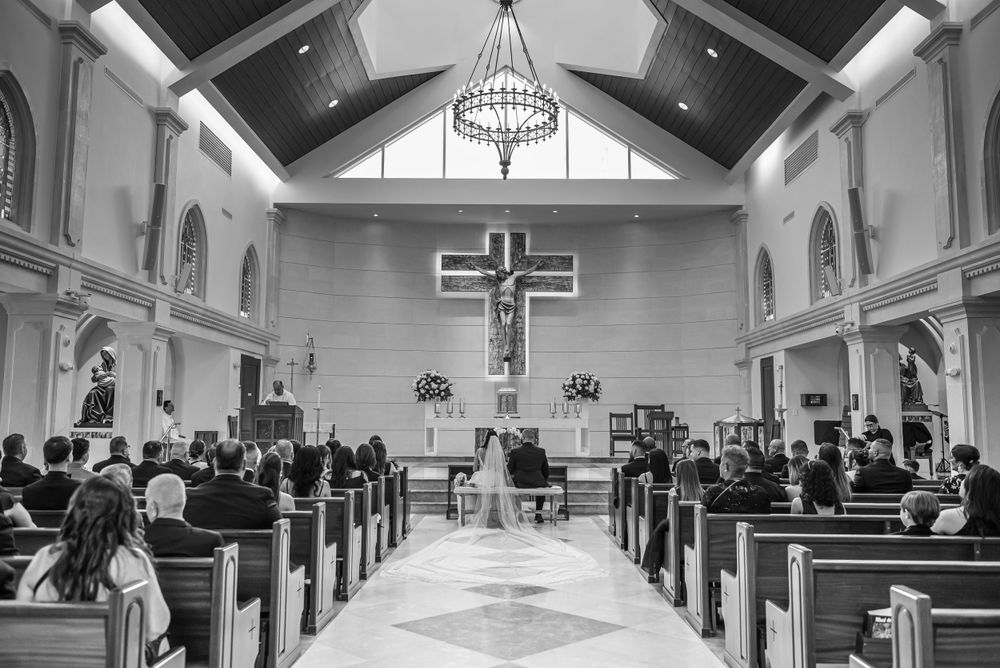 Interior of a traditional church sanctuary with vaulted ceiling, chandelier and wooden pews during a ceremony.