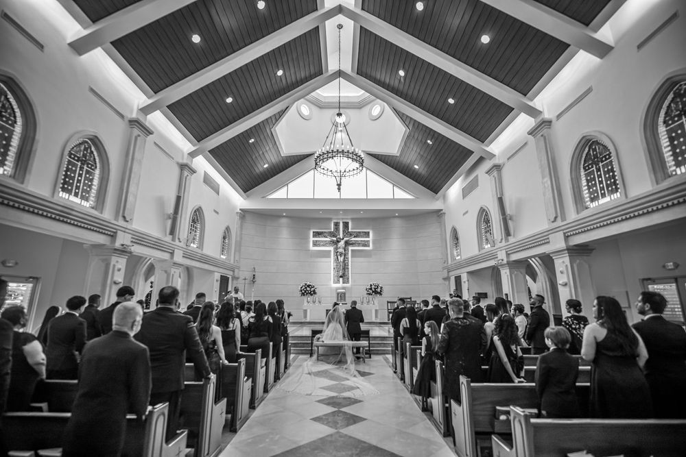 Black and white photo of a church interior with attendees gathered for a wedding ceremony.