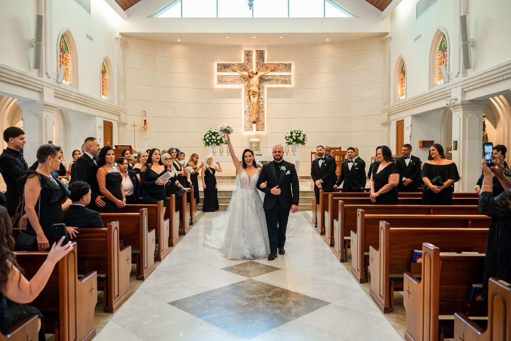 Wedding ceremony in progress inside an elegant church with stained glass windows and wooden pews.