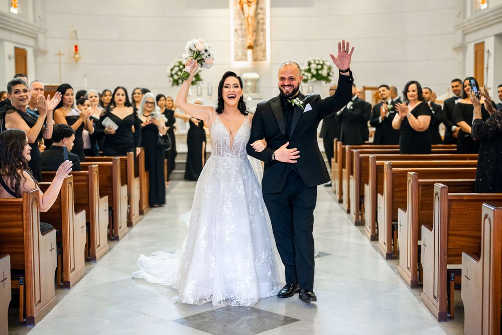 Wedding celebration in a church aisle with guests seated in wooden pews.