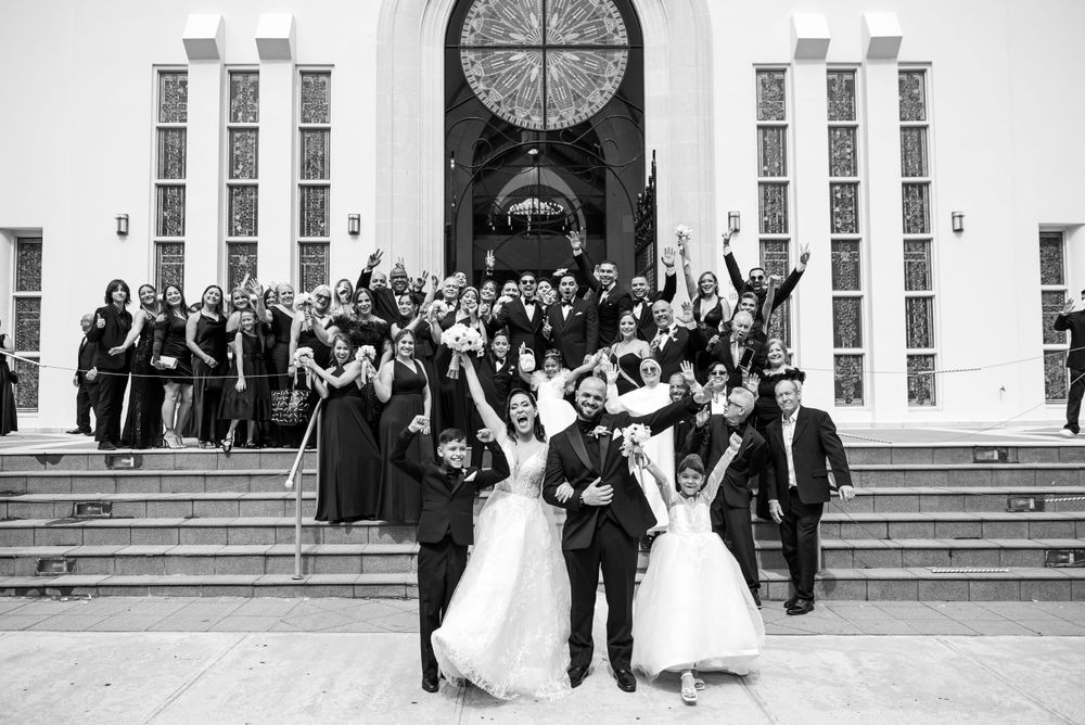 Black and white photo of wedding celebration with group gathered on church steps.