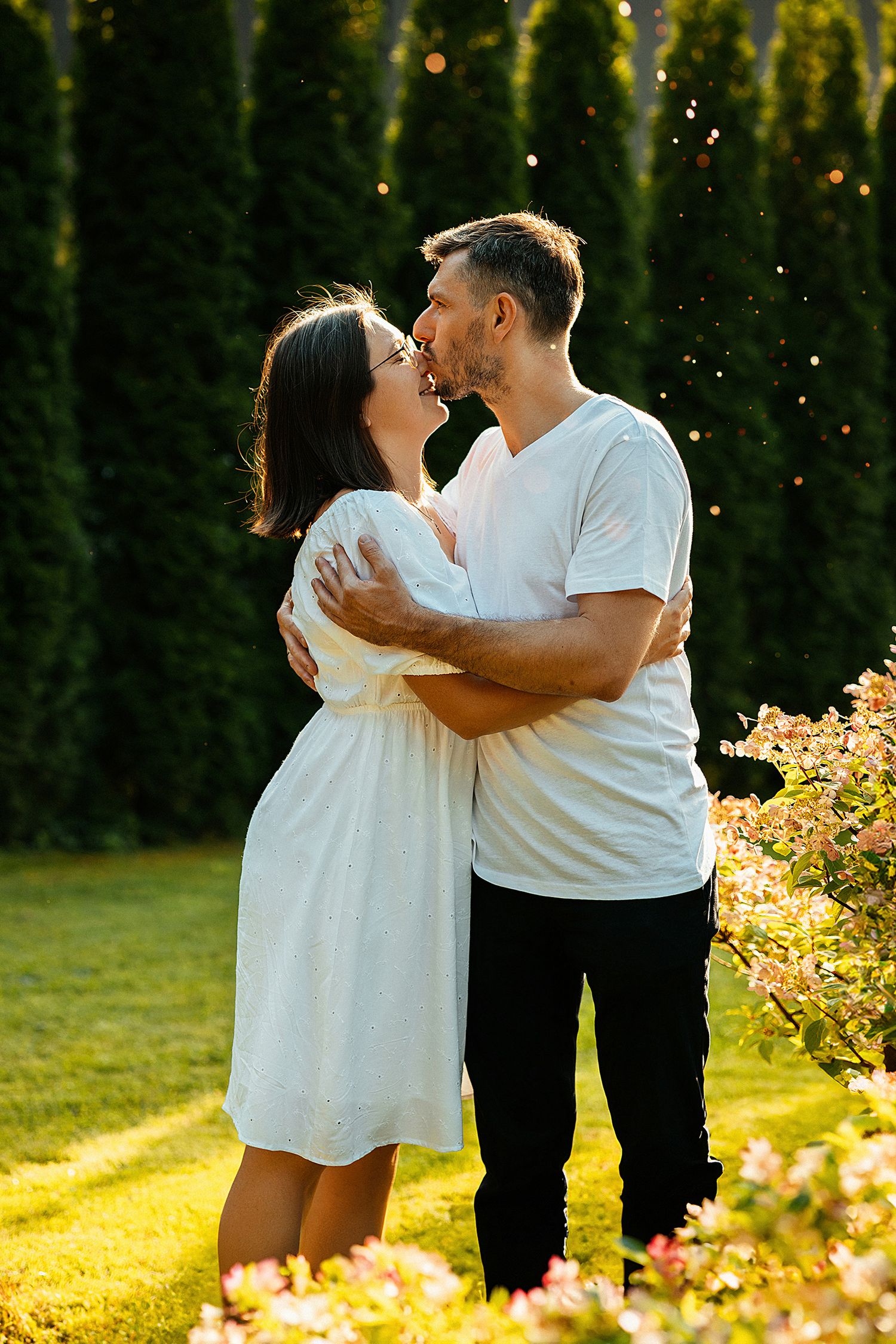 a man  in the setting sun hugs and kisses his wife  on the nose