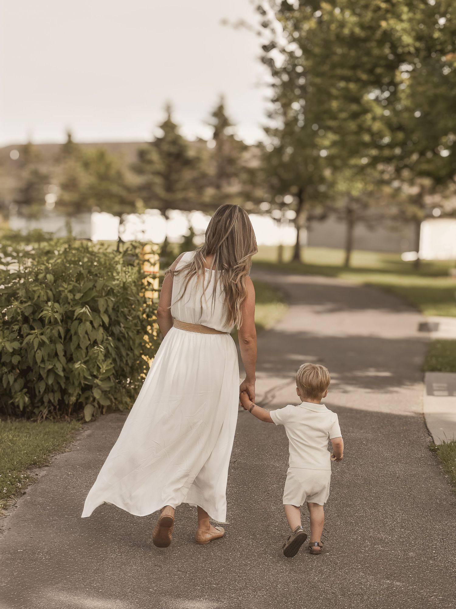Photograph of a family holding hands and walking down a path in a park.  Blue Onion Photography.