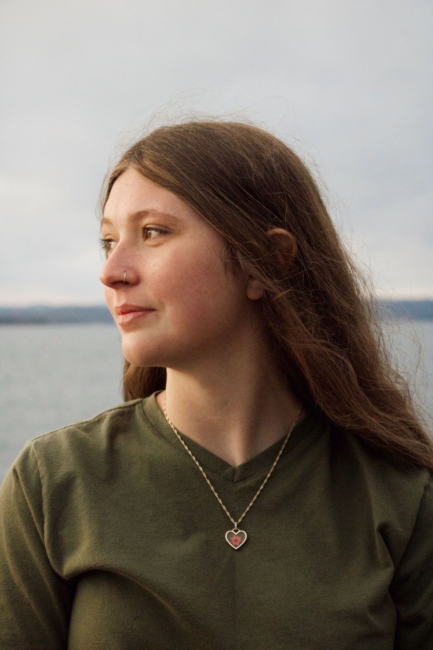 Girl looking off into the distance by the lake at sunset.