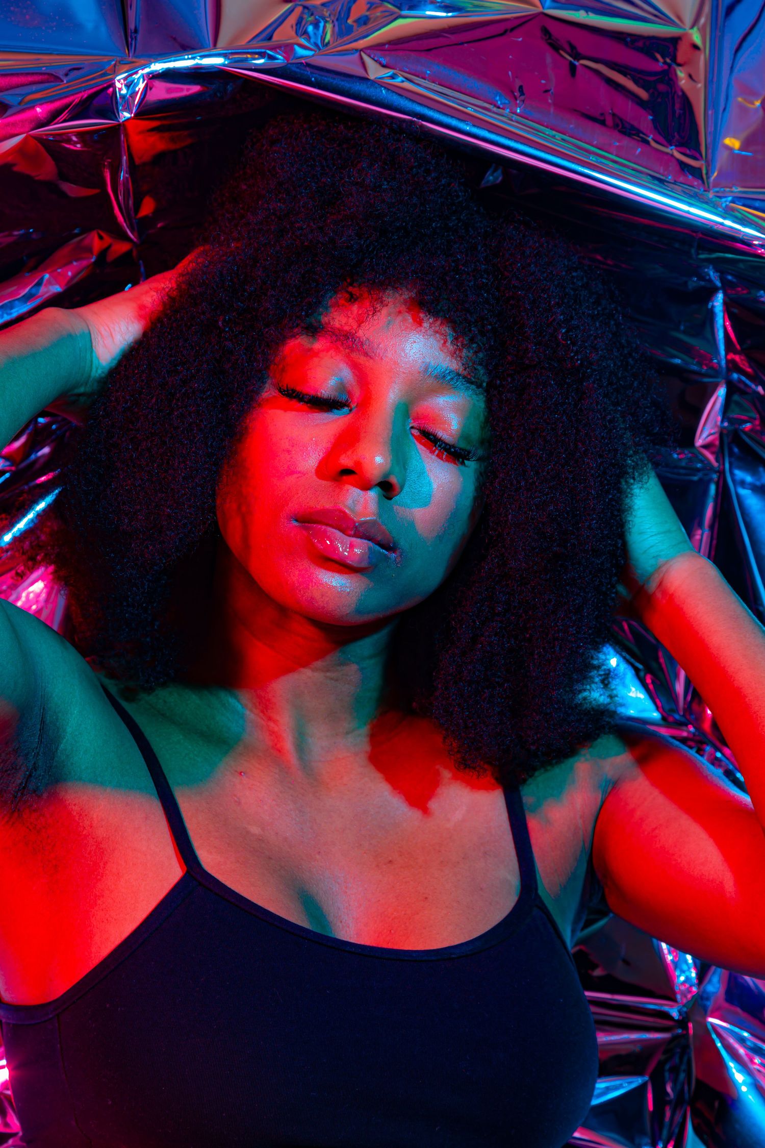 Artistic portrait with prismatic reflections in red and blue lighting creates a dramatic neon-lit atmosphere.