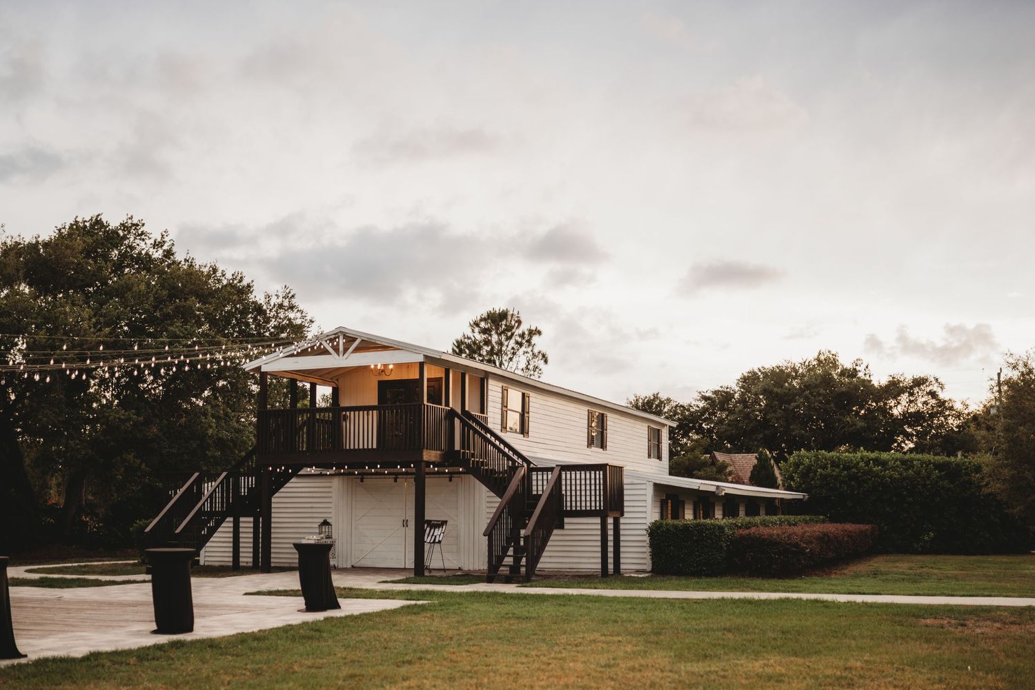 Modern elevated wedding venue building with wooden stairs and white exterior.