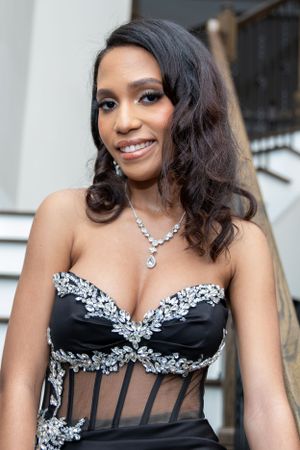 Someone wearing a black and silver embellished formal gown with a sweetheart neckline and diamond necklace.