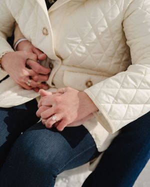 Detail shot of hands with engagement ring against a white quilted winter coat.