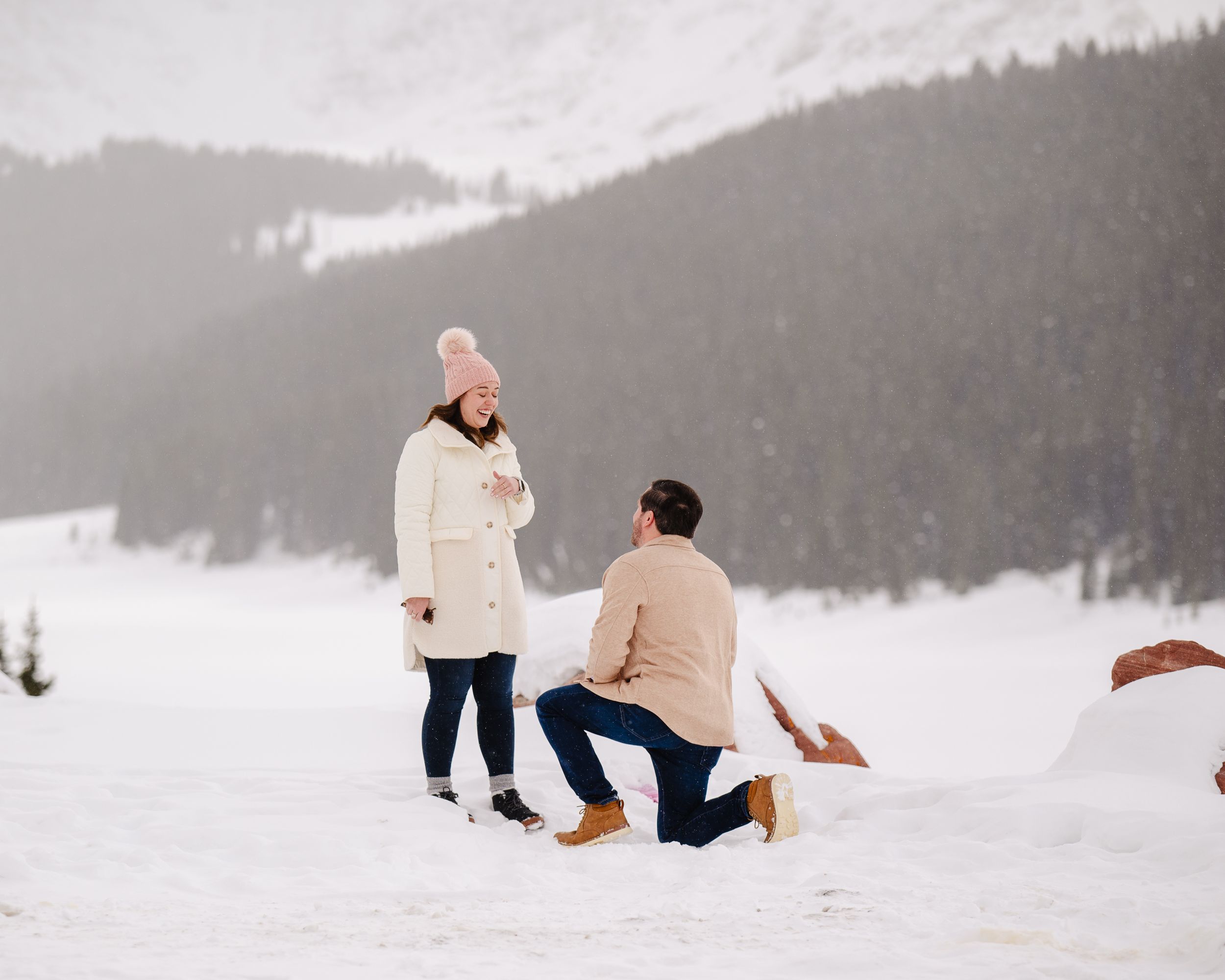 A surprise proposal taking place in a snowy mountain setting.