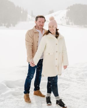 A couple takes a playful winter walk together through fresh snow.
