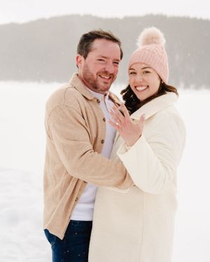 A romantic winter engagement portrait showing off a new ring in the snow.
