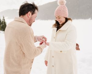 A romantic proposal moment captured in a snowy mountain setting.
