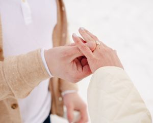Close-up of hands during a ring exchange moment outdoors.