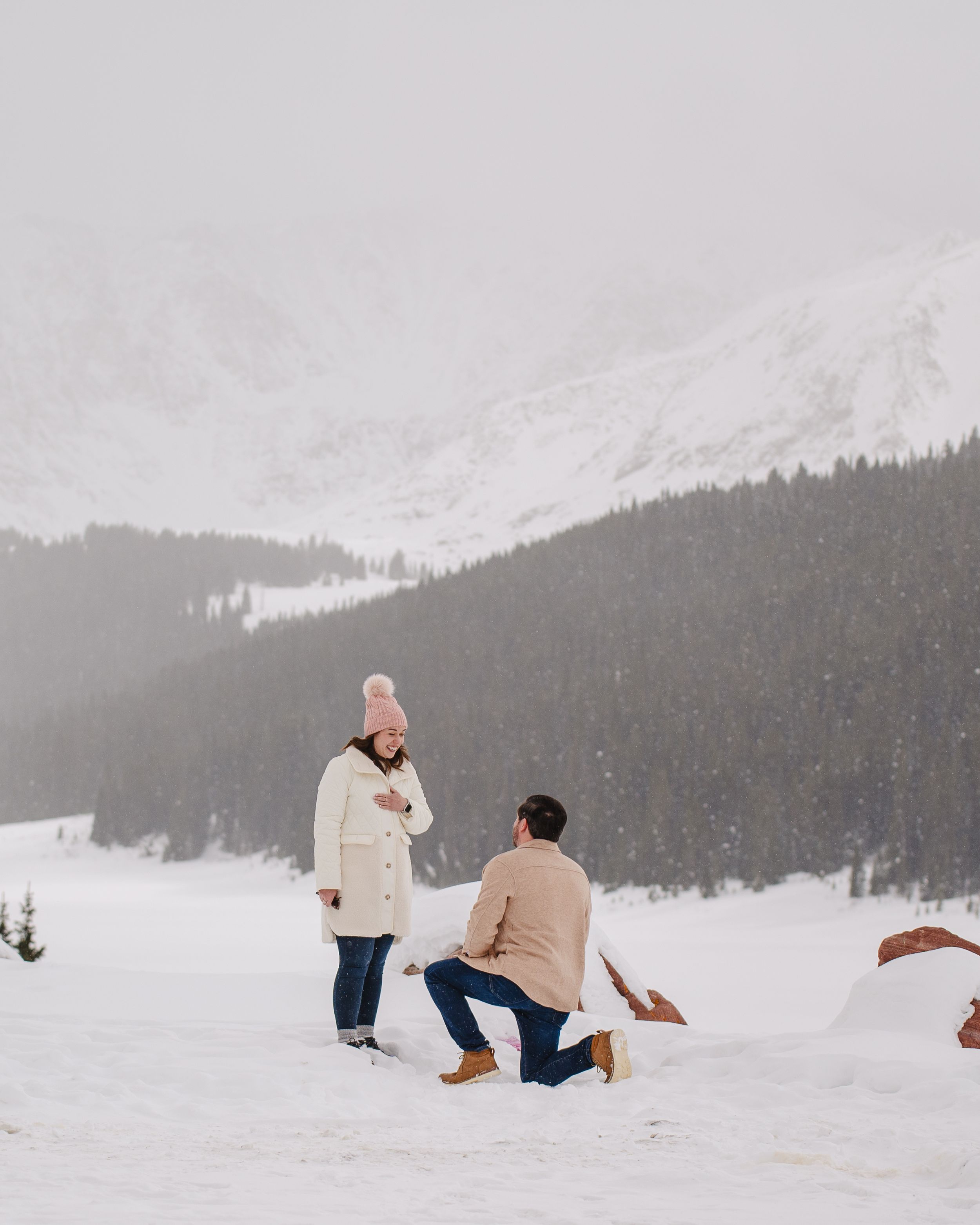 A winter proposal unfolds against snowy mountain scenery.