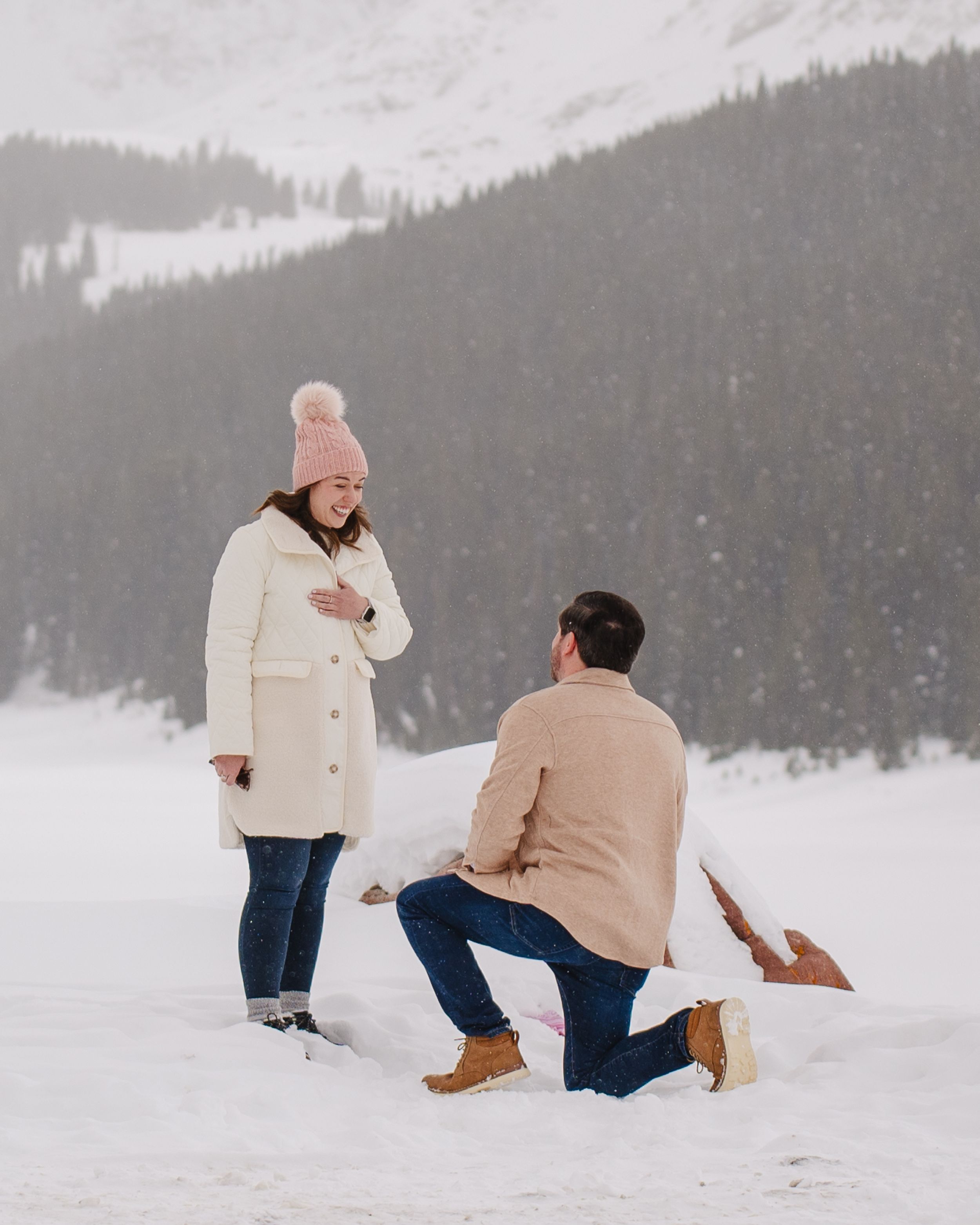 A marriage proposal takes place in a serene snow-covered mountain setting.