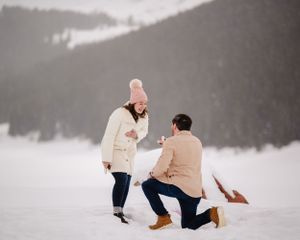 A romantic proposal moment captured in a winter mountain landscape.