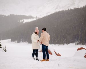 A special moment shared between two people in matching winter outfits on a snowy mountainside.