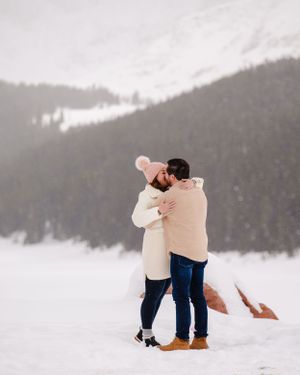 An intimate embrace shared in the snow with majestic mountains in the background.