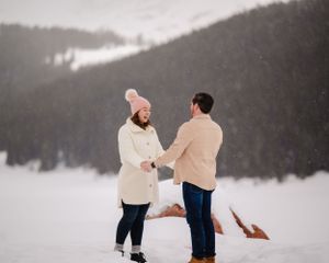 A surprising winter proposal moment unfolds against a snowy mountain backdrop.