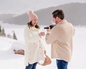 Winter engagement celebration with champagne against a snowy mountain backdrop.