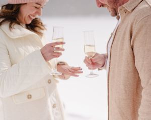Close up of couple toasting with champagne glasses in winter coats.